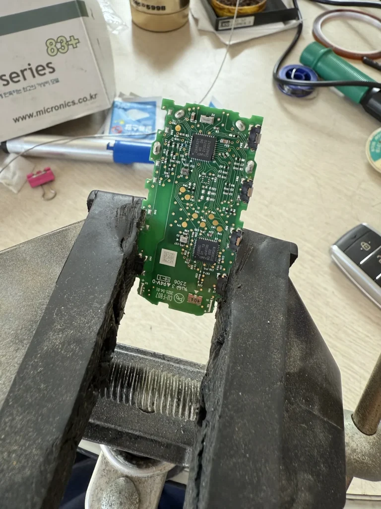 바이스에 고정된 EQ900 스마트키 PCB, 이식 작업 중